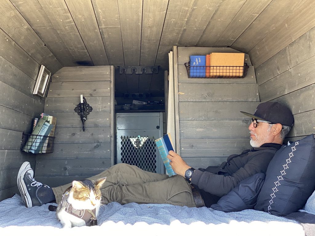 A cat and her human relaxing in their custom camper van at the beach
