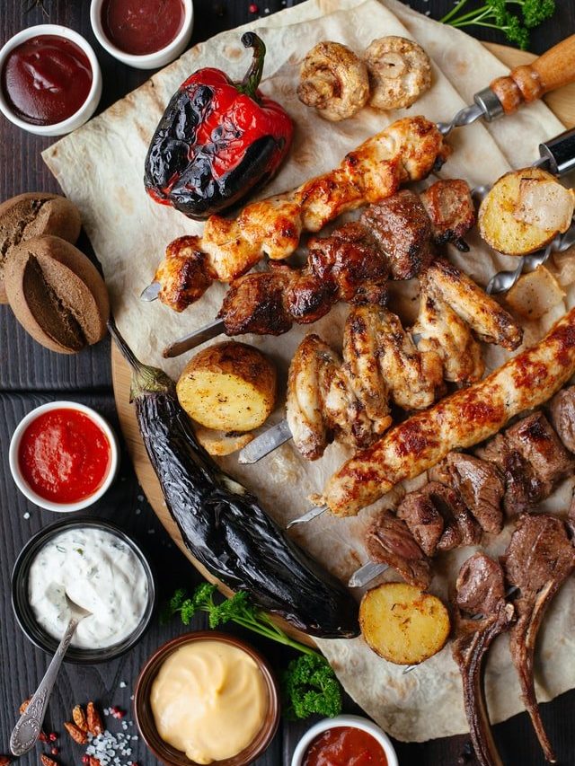 Top down view of a platter of barbecued meats and potatoes with dipping sauces.