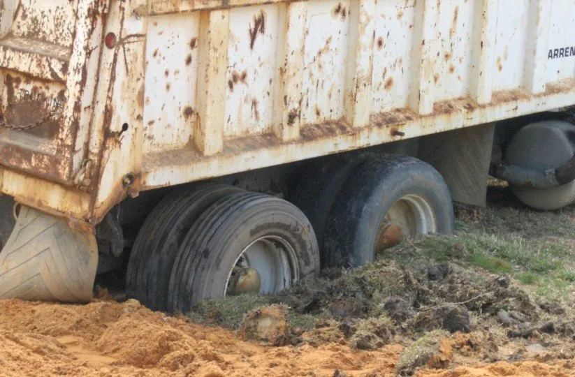 A dump truck stuck in the mud.